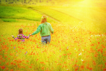 Obraz na płótnie Canvas Two beautiful girls walking in the poppy field