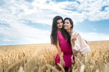 two women in beauty dress possing at wheat field