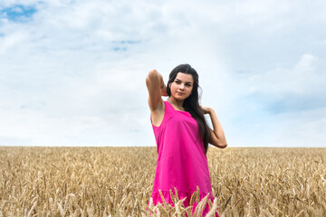 Young woman in  summer dress standing in wheat field and enjoying the life