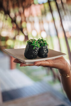 Crop woman with tasty gunkan sushi rolls outdoors