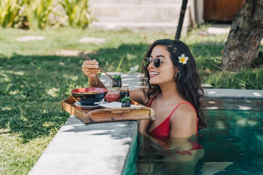 Smiling tourist with tasty noodles in pool during trip