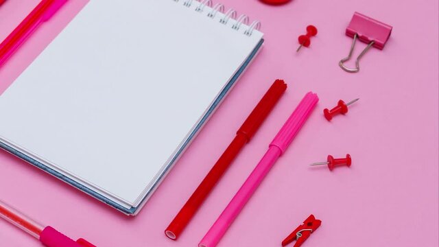 White notebook lies in the form of blank on pink background with red pen with markers. School supplies for girl in pink colors. High quality 4k footage