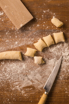 Raw pieces of dough near ribbed board and knife
