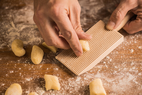 Crop person using board to make gnocchi