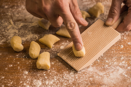 Crop person using board to make gnocchi
