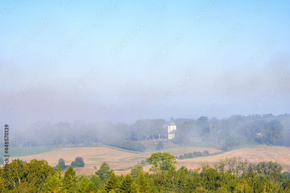 Wall mural Morning mist with a country church