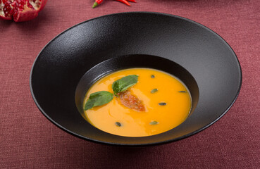 Yellow creamy pumpkin soup served for lunch on a table