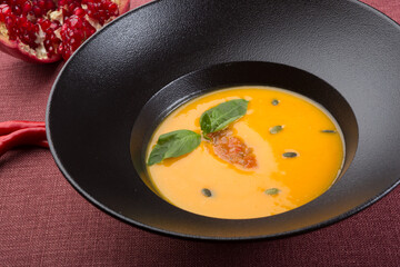 Yellow creamy pumpkin soup served for lunch on a table