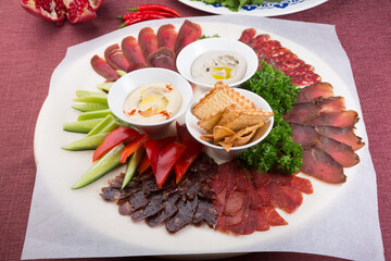 Plate of assorted sliced salted and dried meat served with humus