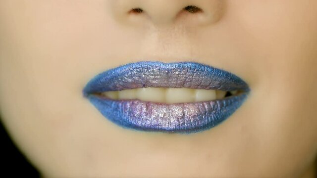 Closeup of a beautiful woman lips with beautiful blue make up sending air kiss . Close up of girl's mouth having flirty emotions and sending air kiss .