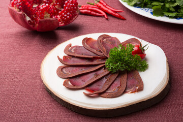Sliced raw smoked meat served on wooden board
