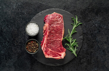 Raw marbled beef New York steak with spices on a stone background