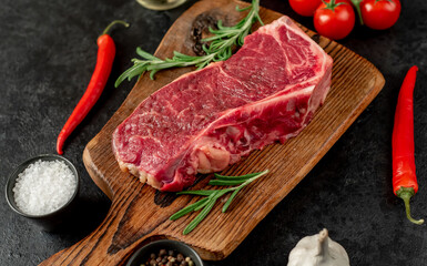 Raw marbled beef New York steak with spices on a stone background