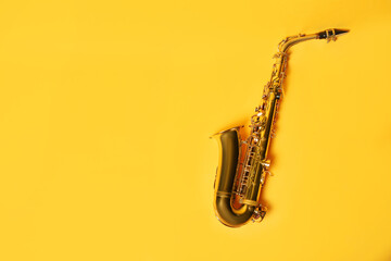 Beautiful saxophone on yellow background, top view. Space for text