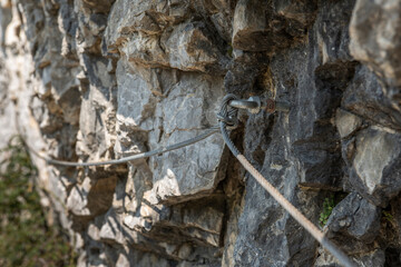 climbing wild wall of stone and cable anchor used by tourists to step forward