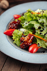 Salad with lettuce and fried duck on wooden background