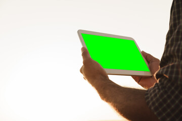 Close up of farmer's hands holding tablet with green screen