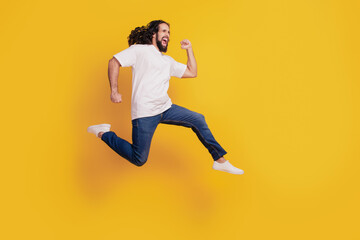 Fototapeta na wymiar Profile portrait of funny positive casual dreamy guy run fast rush jump on yellow background