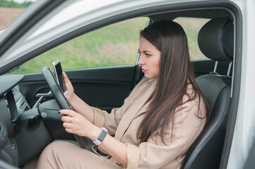 Fototapeta na wymiar Sad woman driver with smartphone sitting inside the car