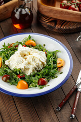 Burrata cheese arugula salad on a rustic wooden background