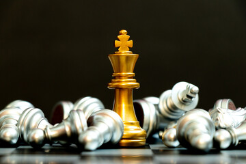 Gold king chess piece win over lying down silver team on black background
