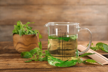 Stinging nettle extract and leaves on wooden background. Natural hair care