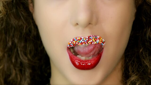 Closeup of a beautiful woman lips with beautiful colorful make up and candy balls sending air kiss . Close up of girl's mouth having flirty emotions and sending air kiss .	
