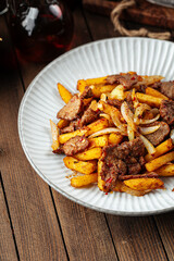Beef meat roast with potato fries on a wooden background