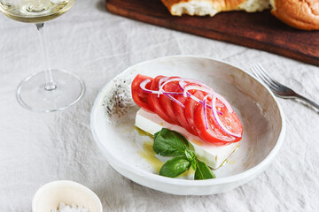 Greek cheese feta with tomatoes, red onion and basil served with wine and fresh baked bread. Selective focus