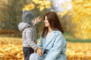 Mother hugs toddler boy ion golden autumn background