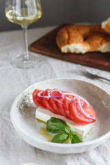 Greek cheese feta with tomatoes, red onion and basil served with wine and fresh baked bread. Selective focus