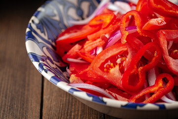 Uzbek achichuk salad with tomatoes and pepper on a wooden background