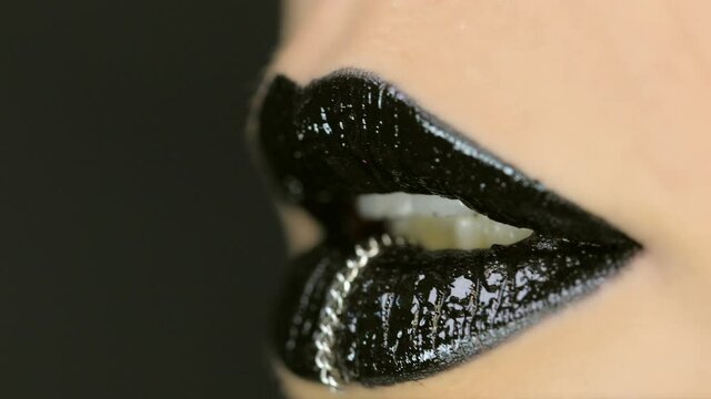 Closeup of a beautiful woman lips with beautiful black makeup and piercing sending air kiss . Close up of girl's mouth having flirty emotions and sending air kiss 