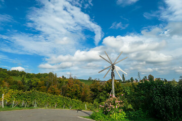 A lush wine region is South Styria, Austria. The wine plantations are stretching over a vast territory, over the many hills. A small windmill towering above the plantation. Idyllic landscape