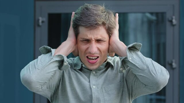 Too much noise. Anxious young professional shout NO cover ears with palms unable to hear loud music noisy sound. Angry frustrated businessman employer get mad hate listening disturbing noise outdoors