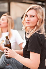 Pretty young women eating hamburger and drink beer outdoor on the street