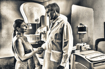 Male doctor shaking hand with female patient in hospital