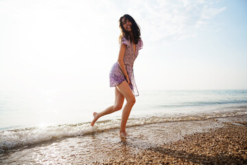 Fototapeta na wymiar Portrait of young woman walking on the beach on sunrise