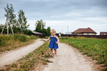 Fototapeta na wymiar Little girl of two years old on country road.