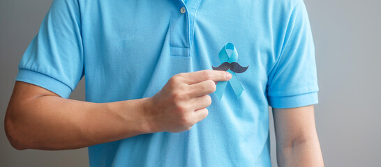 November Prostate Cancer Awareness month, Man holding Blue Ribbon with mustache for supporting...