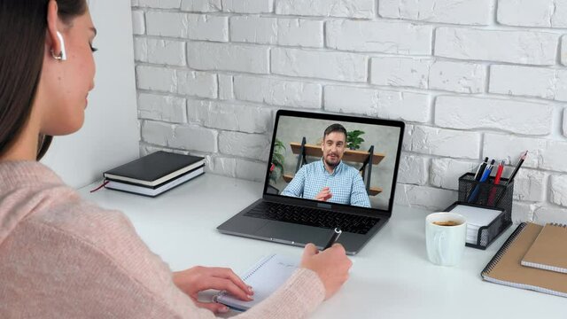 Smiling man tutor in computer screen talk teaches student remote webinar course lesson, distance education. Woman at home study online video call webcam chat laptop listen teacher, writes in notebook