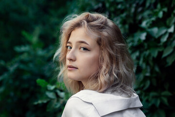 Portrait of a beautiful woman in white clothes on a background of green leaves