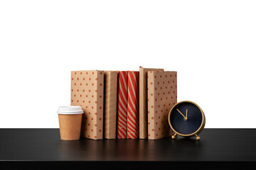 Alarm clock, stack of books and cup on tabletop against white background
