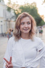 Portrait of a beautiful young woman in white clothes on the alley of the city