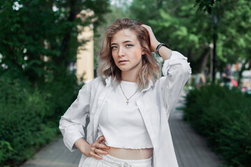 Portrait of a beautiful young woman in white clothes on the alley of the city