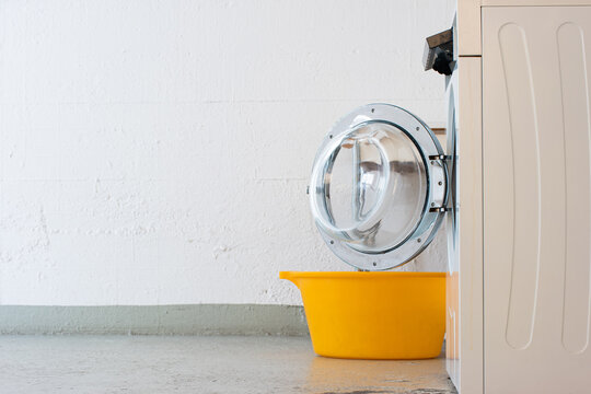 Landry Room Washing Machine Open Door And Yellow Plastic Basket. Side View No People