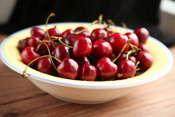 Ripe juicy red cherries in a yellow plate