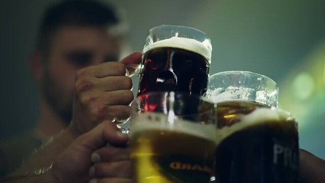 Beer party in a pub. People have fun, clink glasses of beer and drink. Assorted pints of beer.