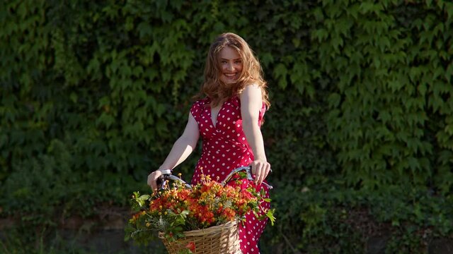 Woamn with flowers on her bicycle tossing hair in park