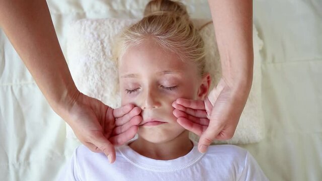 Masseur doing face massage to child.